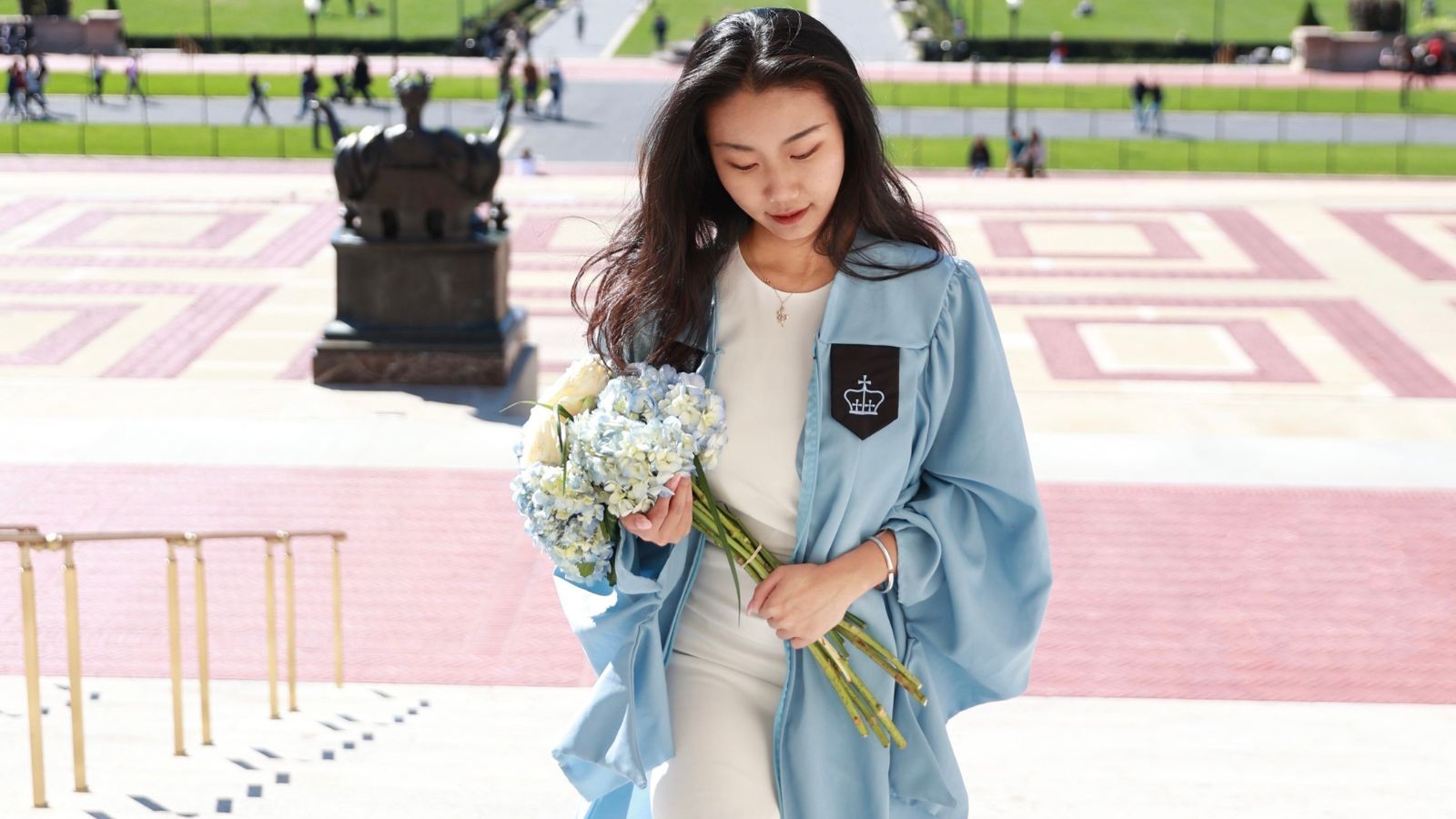 Bingruo Xu in graduation gown walking up Low Steps